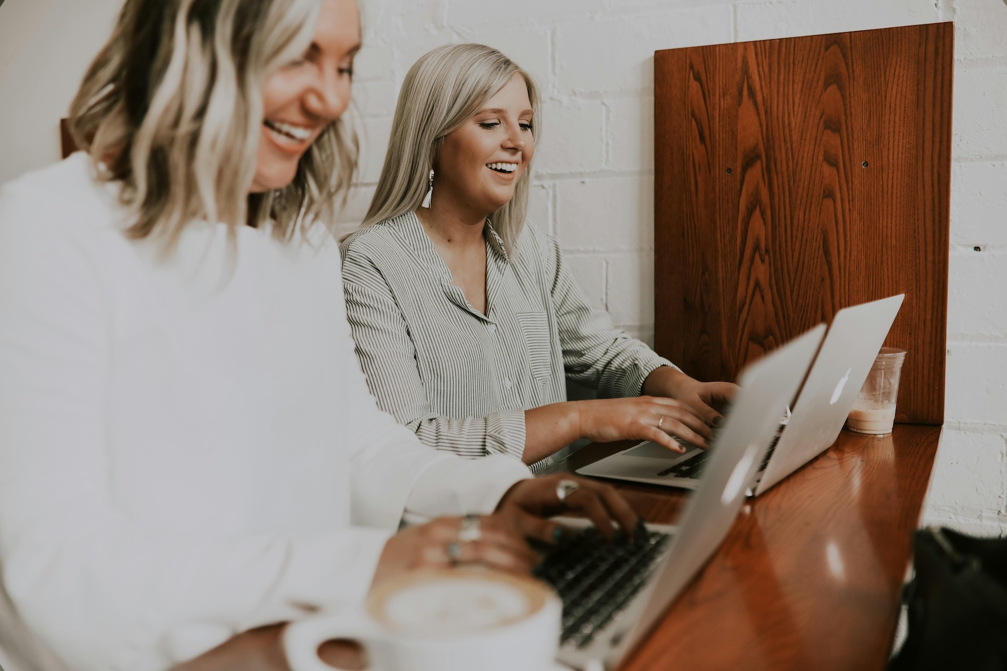 two woman on laptops smiling